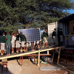 De leerlingen helpen bij het uitladen van de zonnepanelen. 